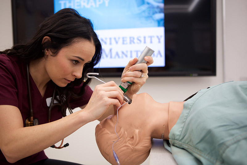 A respiratory therapy student practices her skills on a manikin..