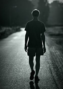 A man walks down a road in silouhette