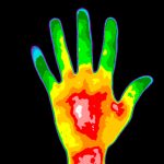 A thermal image of a human hand has glowing regions of blue, green, yellow and red.