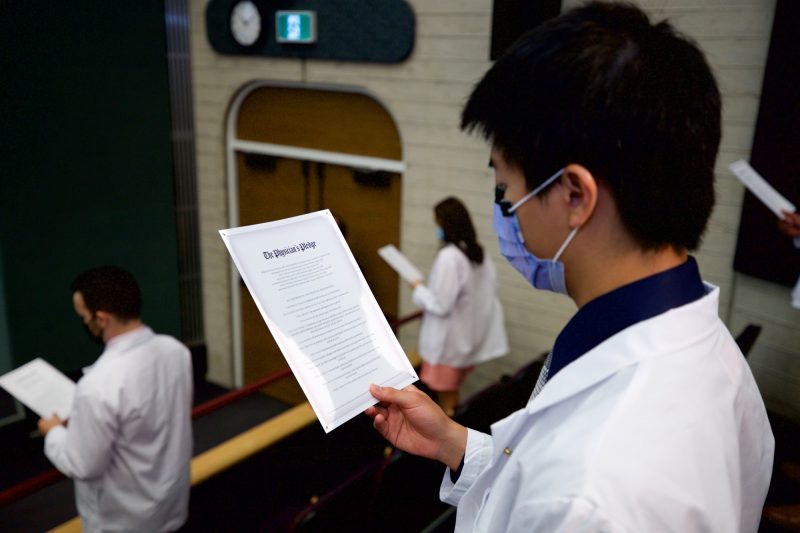 Students hold copies of the Physician’s Pledge while reading it.