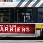 A public transit bus with a red advertisement on the side that says "Getting past the barriers" on it.