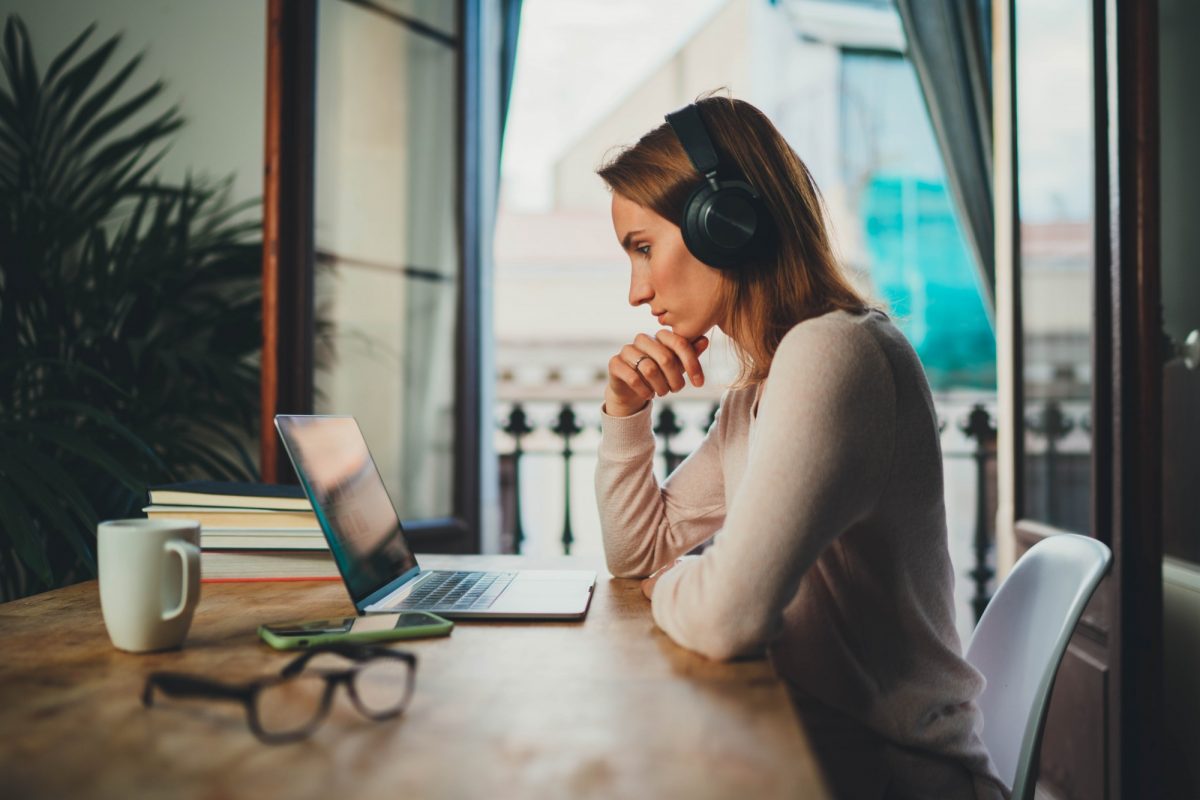 Woman by a window contemplates the future as she gazes into her laptop