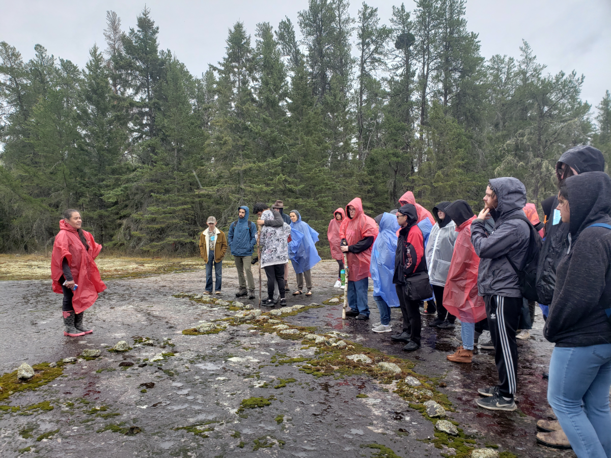 Elder Diane Maytwayashing shares teachings about the Bannock Point petroforms with Land and Water participants.