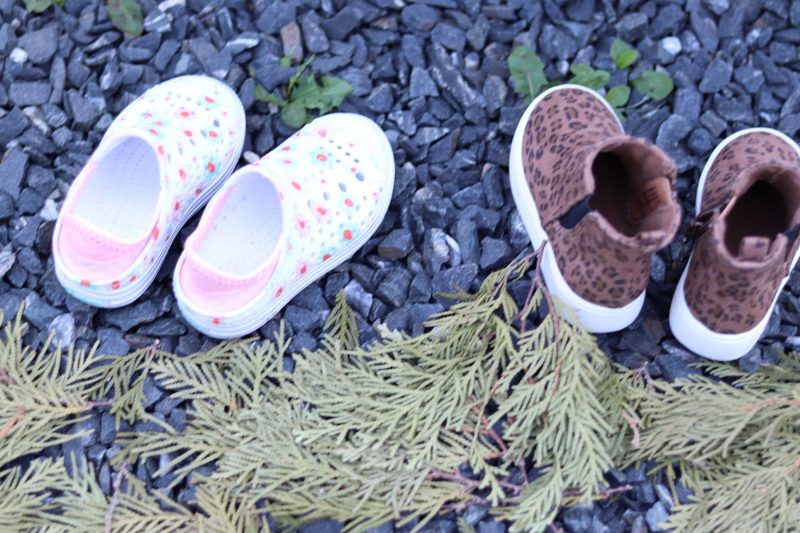 Closeup of two pairs of small children's shoes, one pink-and-white and one brown..