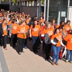 A large group of people wearing orange shirts that say Every Child Matters walk on the Fort Garry campus of the University of Manitoba.