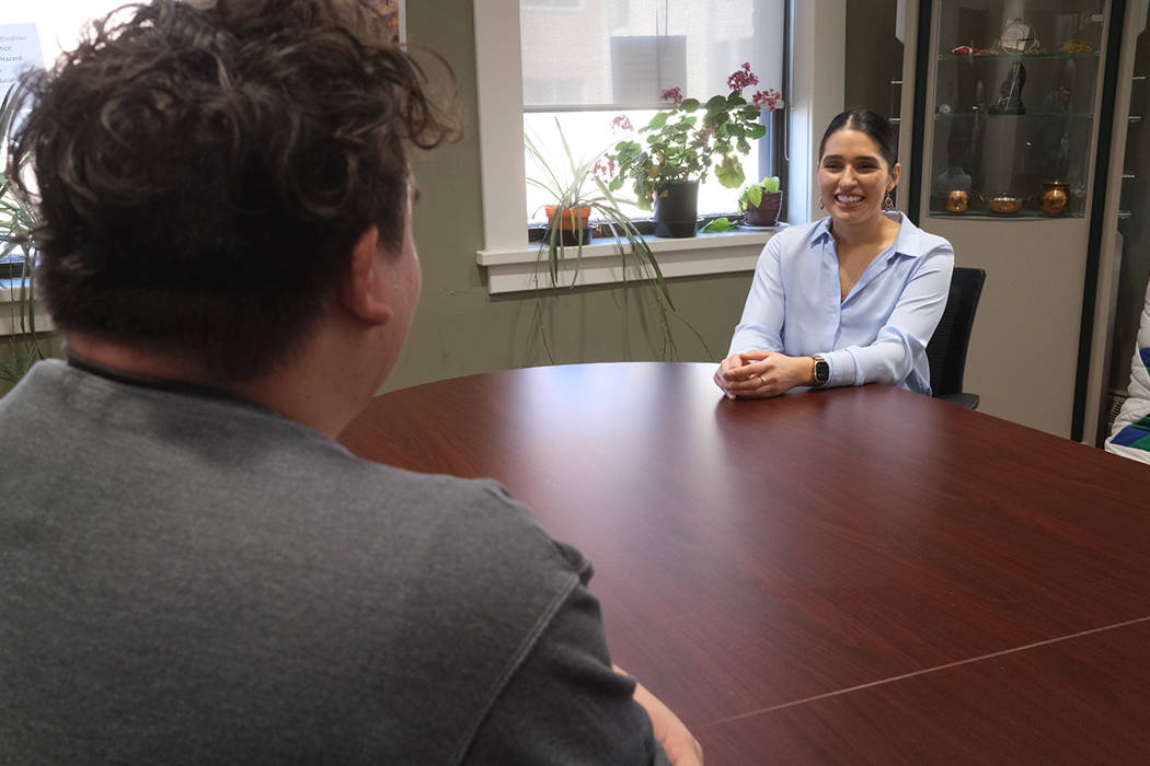 Gabrielle Wilson smiles as she sits across from a student at a boardroom table.