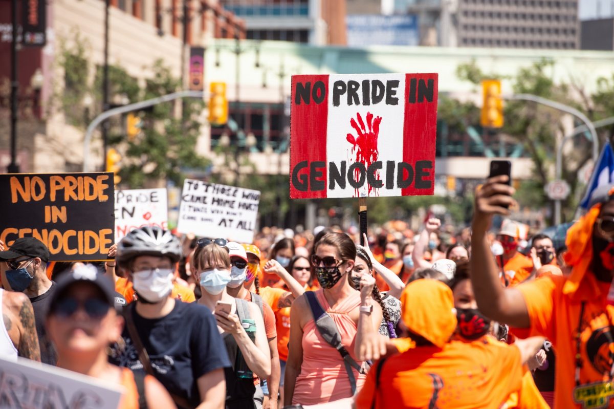 Rally participants hold up signs and wear orange shirts as they march in support of residential school survivors and the families of missing and murdered Indigenous children in Winnipeg on. July 1, 2021. THE CANADIAN PRESS/Mike Sudoma