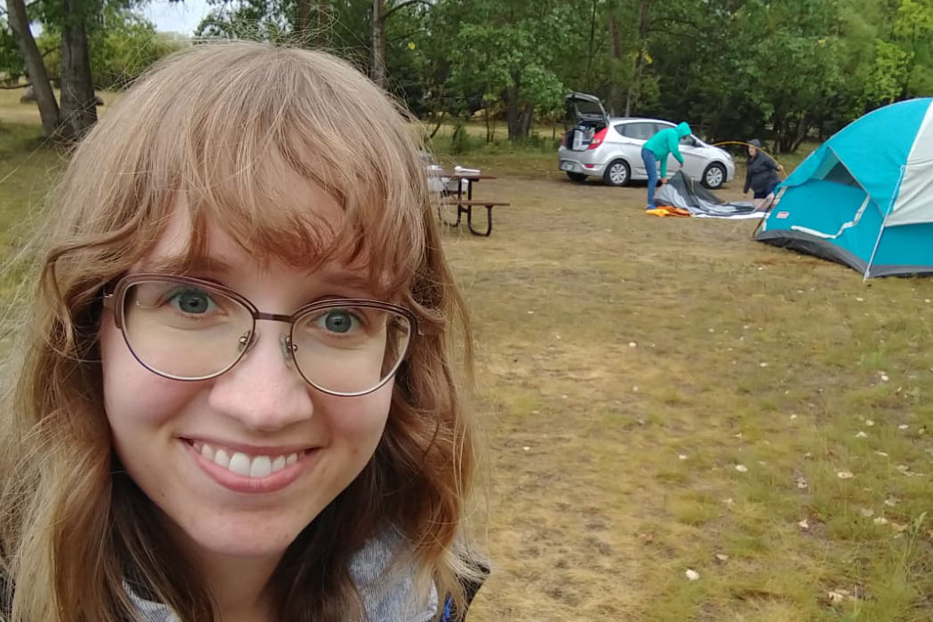 Angela Woodbury in font of a campsite.