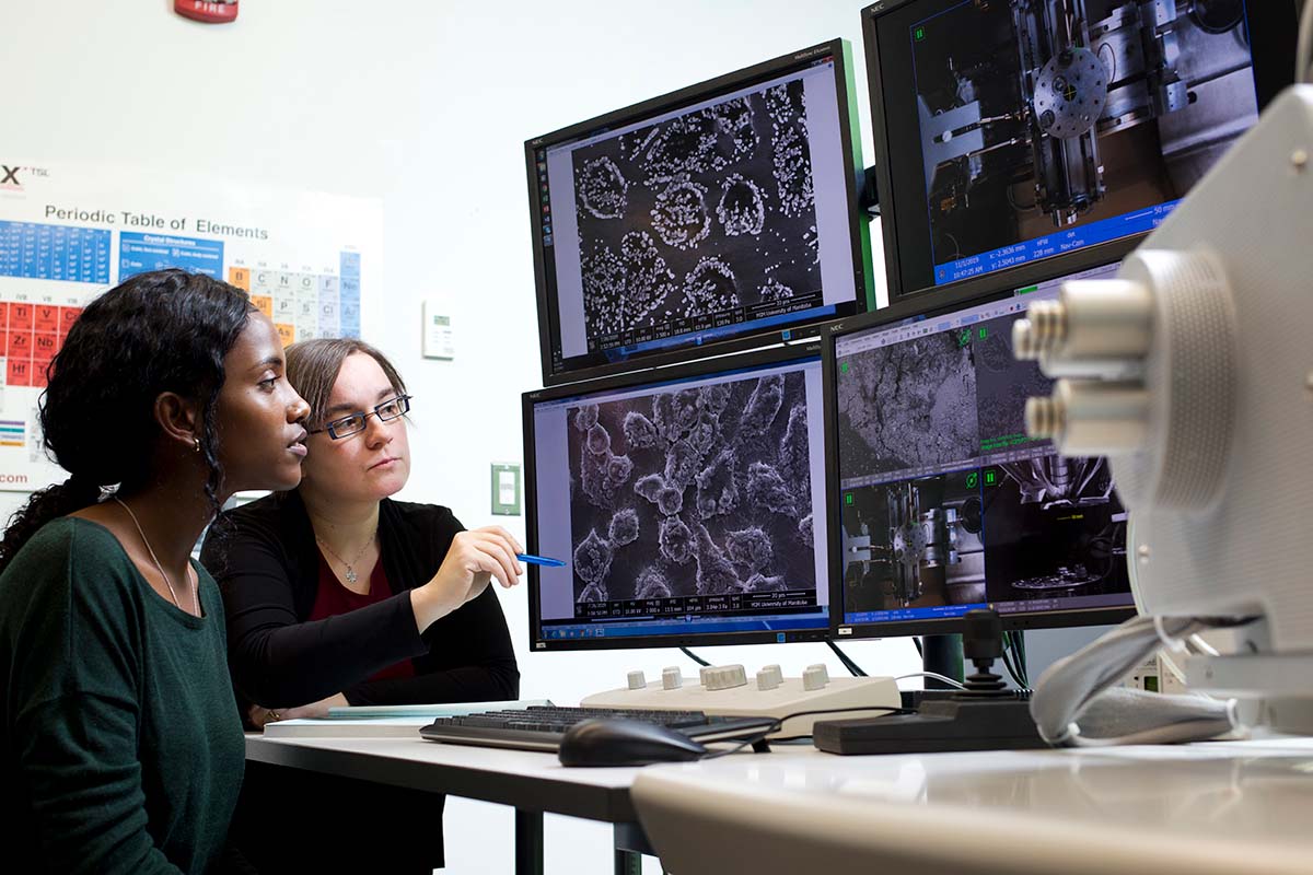 Two people analyzing an image on a screen. Photo taken pre-pandemic.