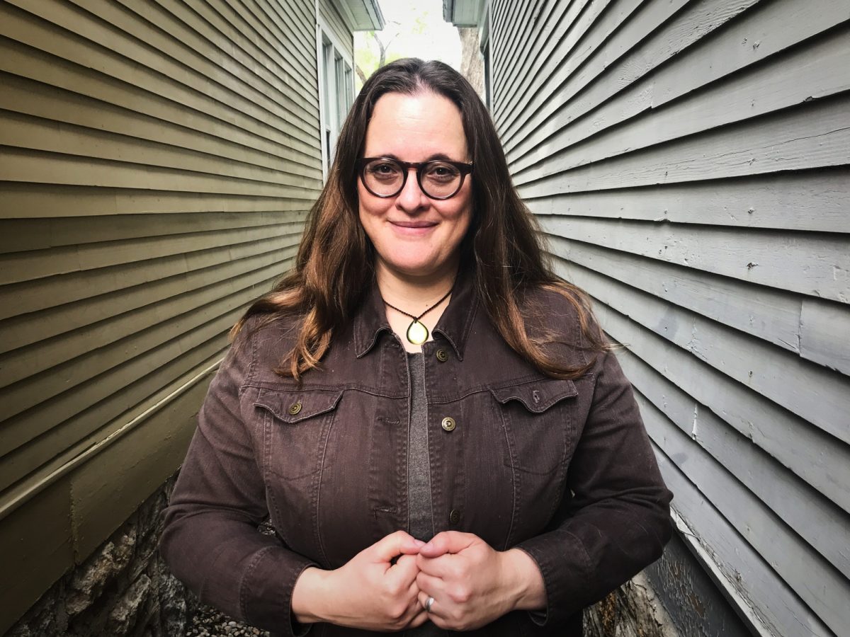 Headshot of woman standing in between two houses clad with siding.