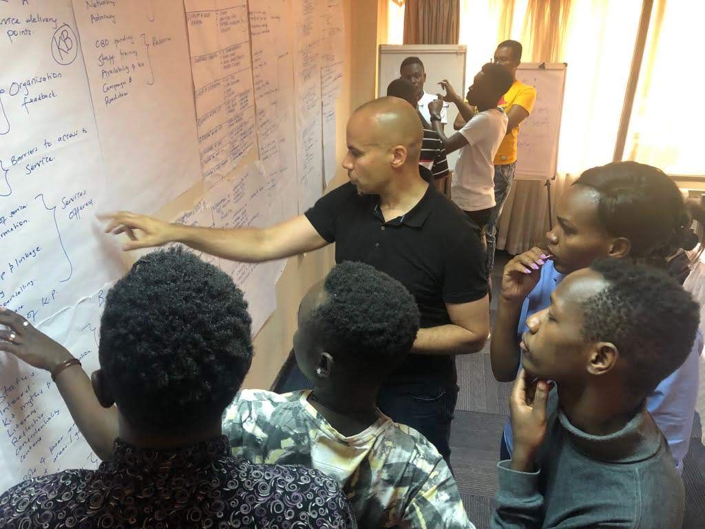 Dr. Robert Lorway points out information on a bulletin board to four Kenyan activists who are gathered around him.