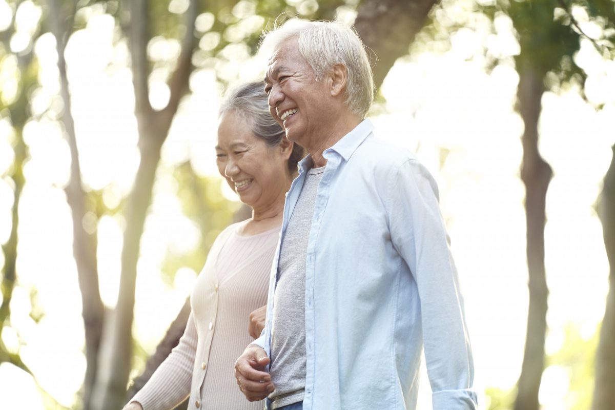 A mature couple walks through the park holding hands