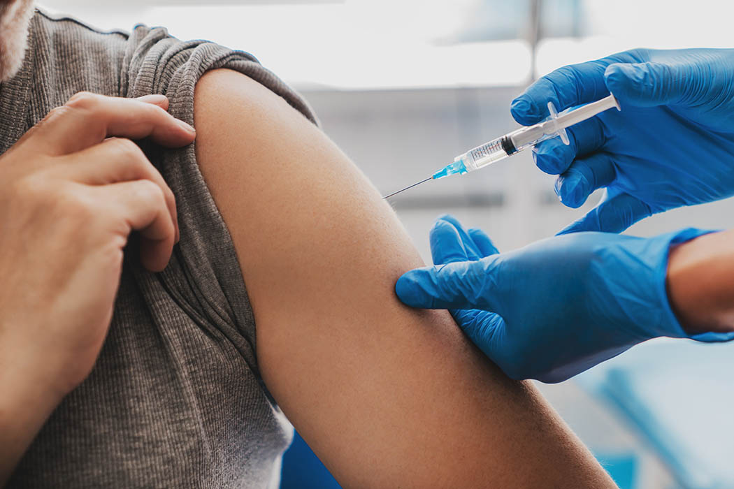 A health-care worker inserts a needle into a patient's arm.