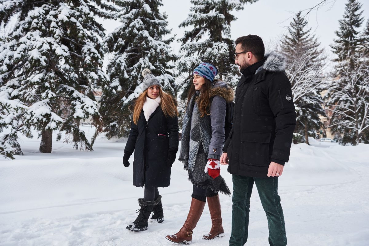 three students walk across campus in the snow