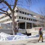 A student walks in front of UMSU University Centre on a winter day