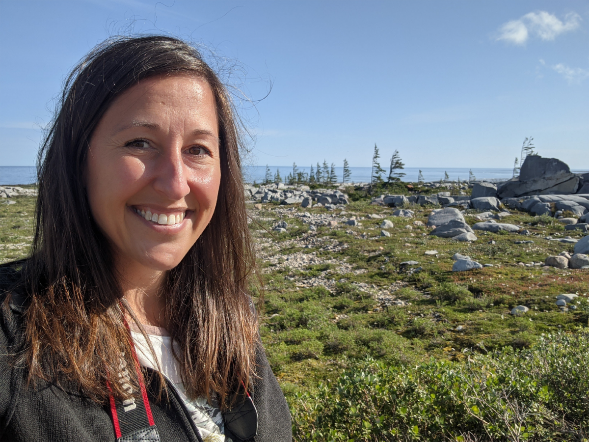 Asper M B A student, Jessica Burtnick, smiling with the green Churchill tundra behind her.