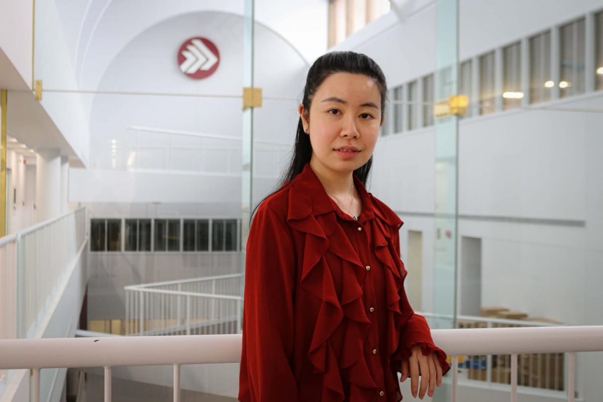 Asper School of Business student Sirius Zhang wearing a red shirt in the Drake building atrium.