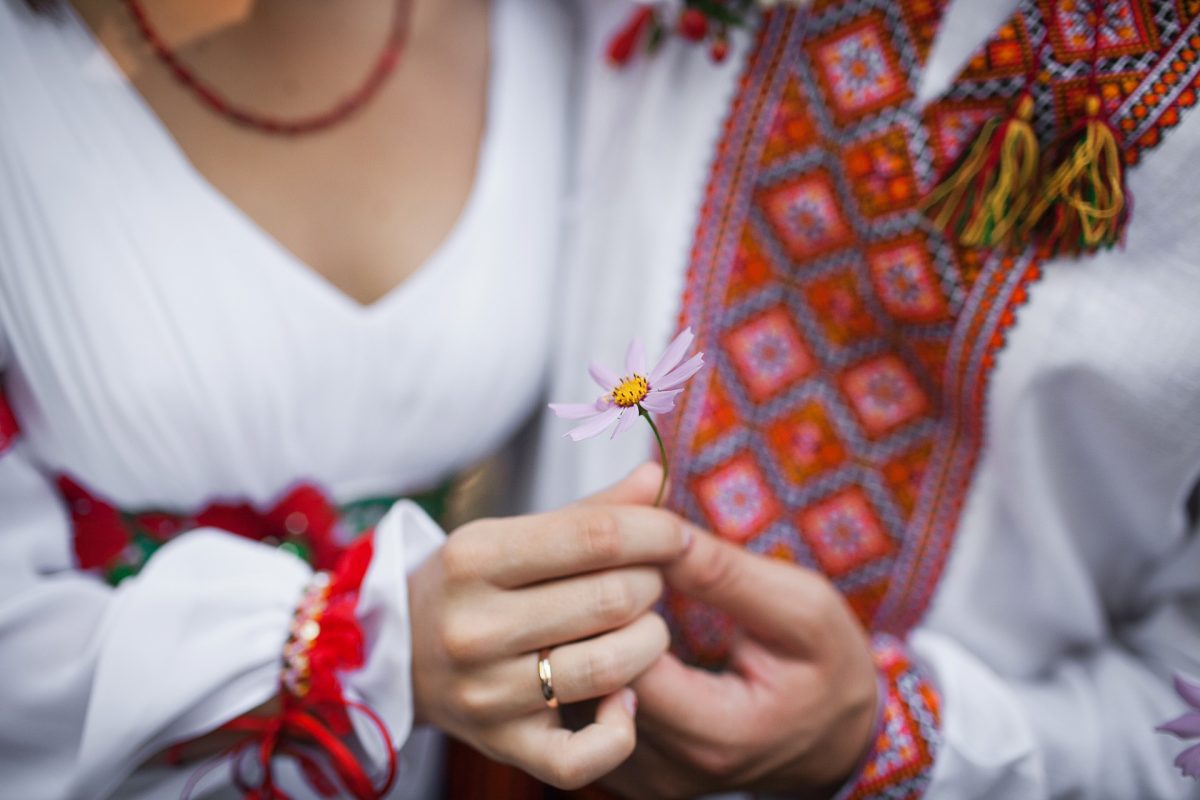 People in traditional Ukrainian clothing hold a flower