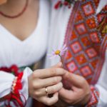 People in traditional Ukrainian clothing hold a flower