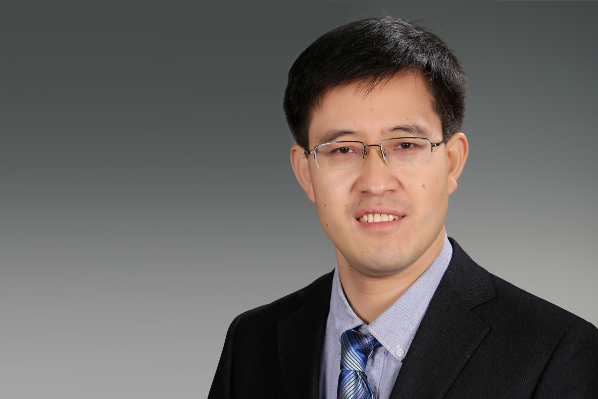Asper professor Lei Lu wearing a black suit and tie, smiling with glasses on.