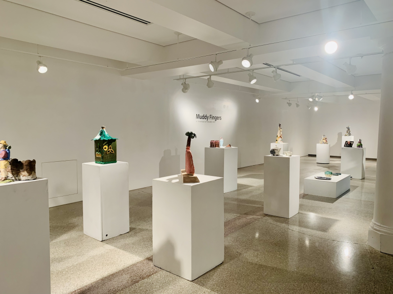 An overview photo of the ceramics exhibition featuring several white plinths with various colourful ceramics on display