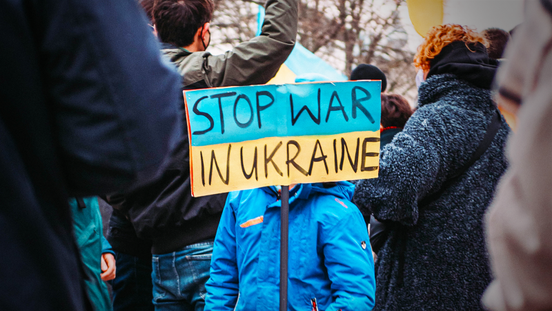 Child holding sign "Stop War in Ukraine" in the middle of a protest
