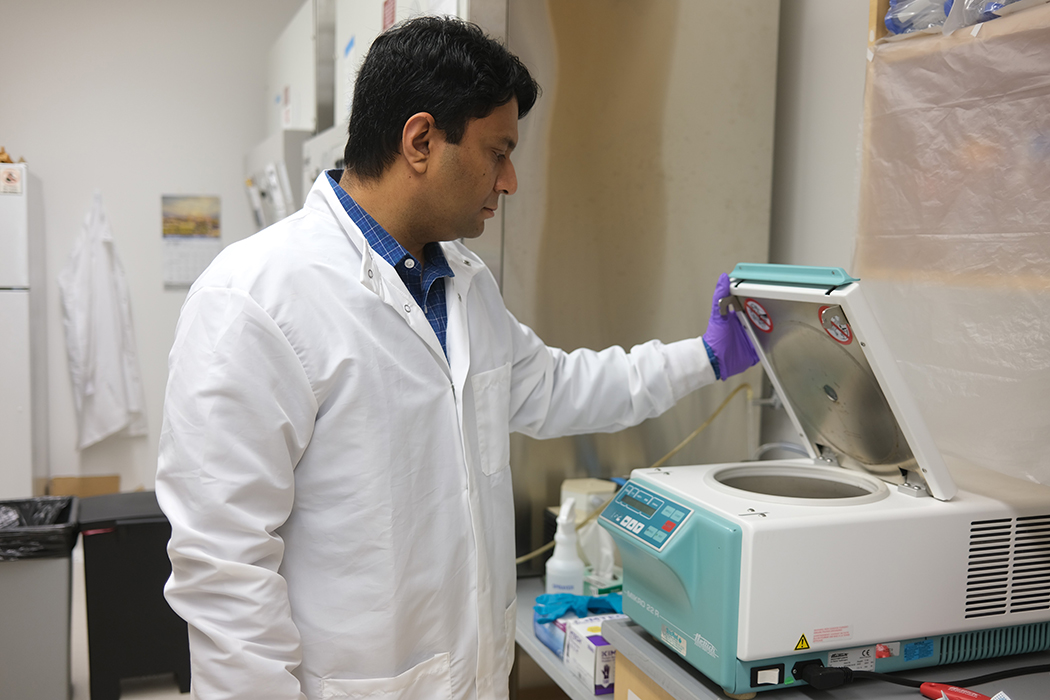 Dr. Abdullah Al Maruf lifts the lid of a microcentrifuge and looks inside.