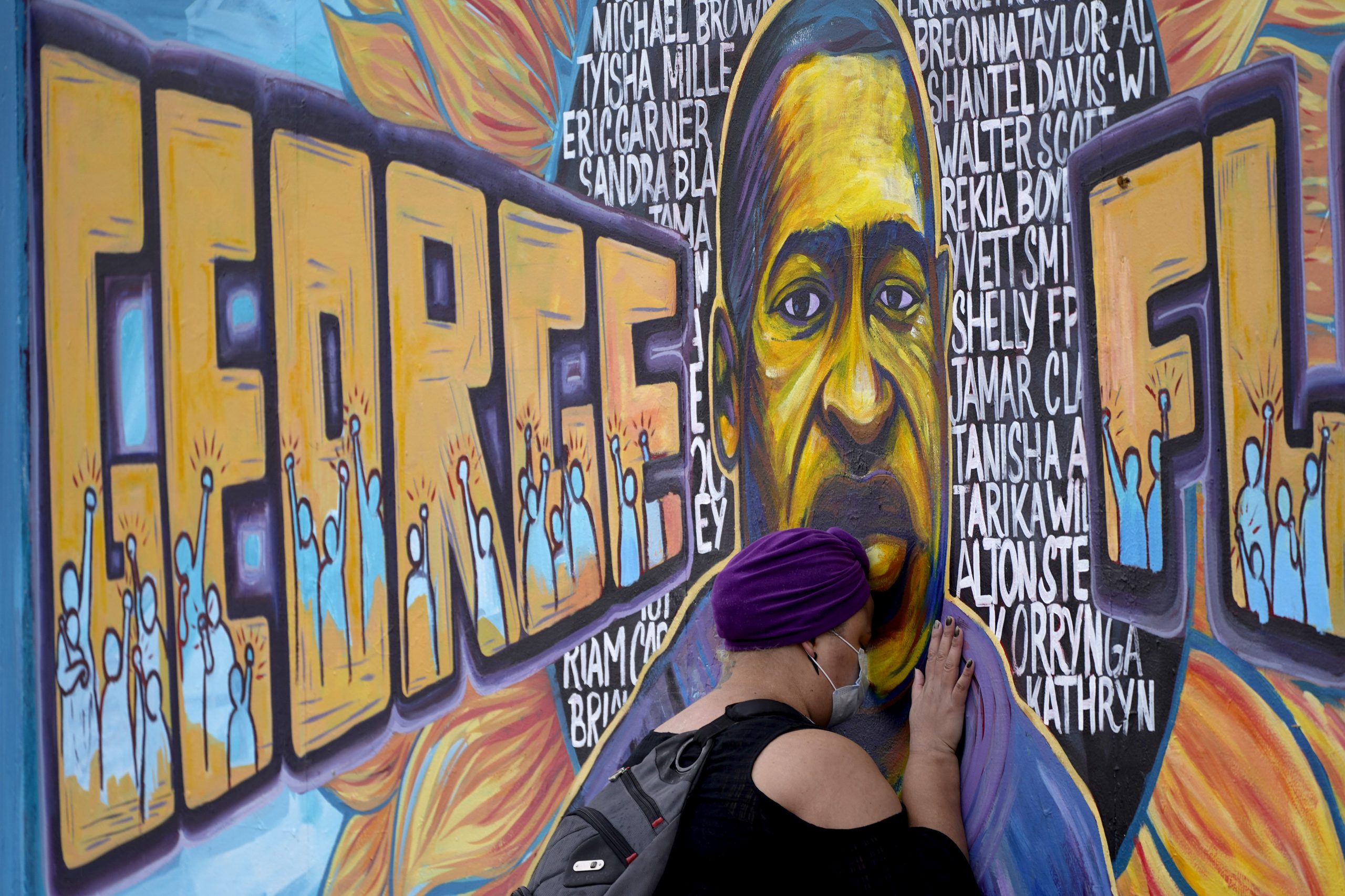 A woman pays respect to George Floyd at a mural at George Floyd Square in April 2021. (AP Photo/Julio Cortez)