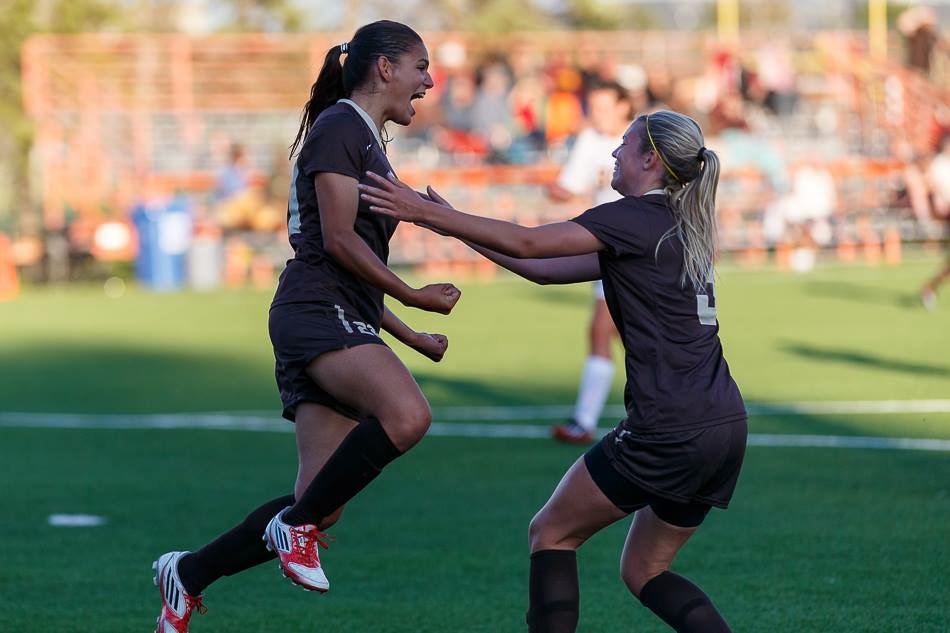 Mavignier and teammate jump in celebration on the soccer field, wearing Bisons jerseys