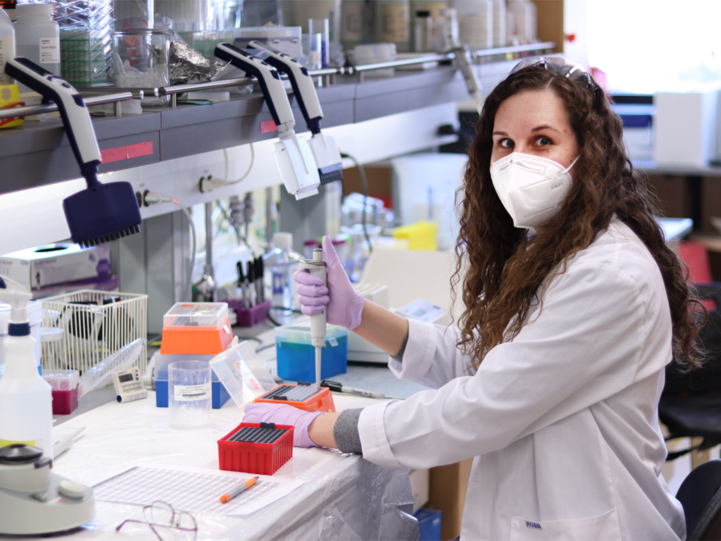 A graduate student wearing a lab coat works in a pharmacy lab.