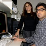 Dr. Seyed Mojtaba Hosseini sits at a computer and Dr. Soheila Karimi stands next to him.
