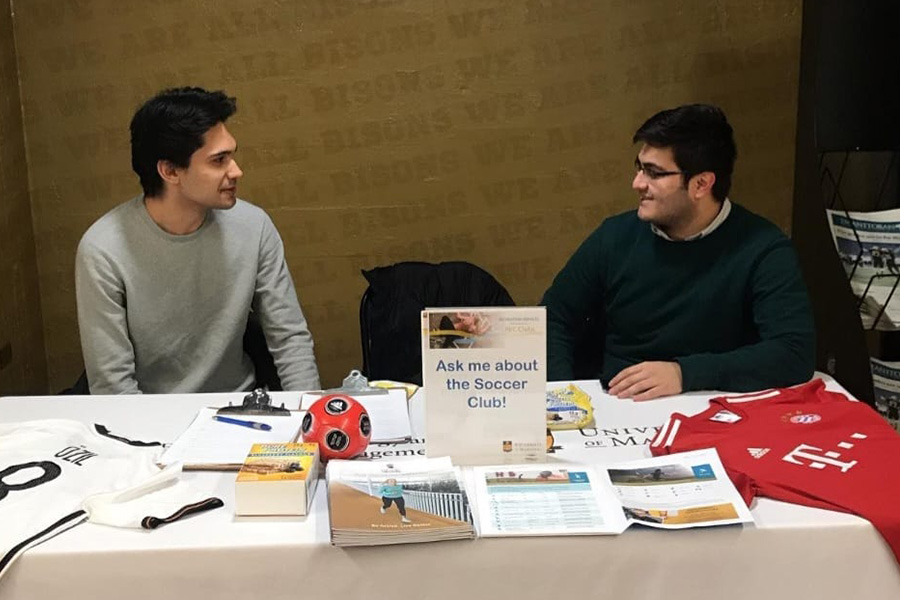 Liam Grenier and Akbar Rizvi sit behind a table in the ALC, smiling