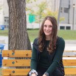 Student Gillian Laninga sits on a bench outside the College of Nursing building at Fort Garry Campus.