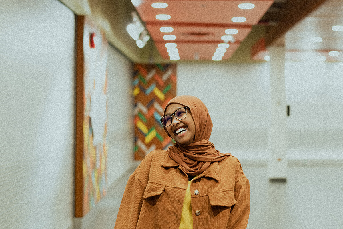 Asea Hussein smiles in an art gallery wearing a matching jacket and hijab.