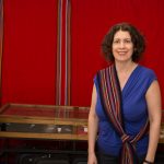 Michelle Driedger wearing a Metis sash in front of a red background