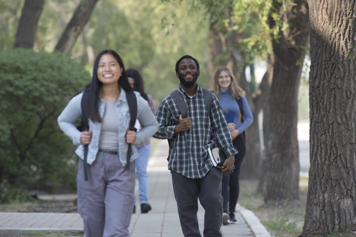 Students walking on campus with trees in background.