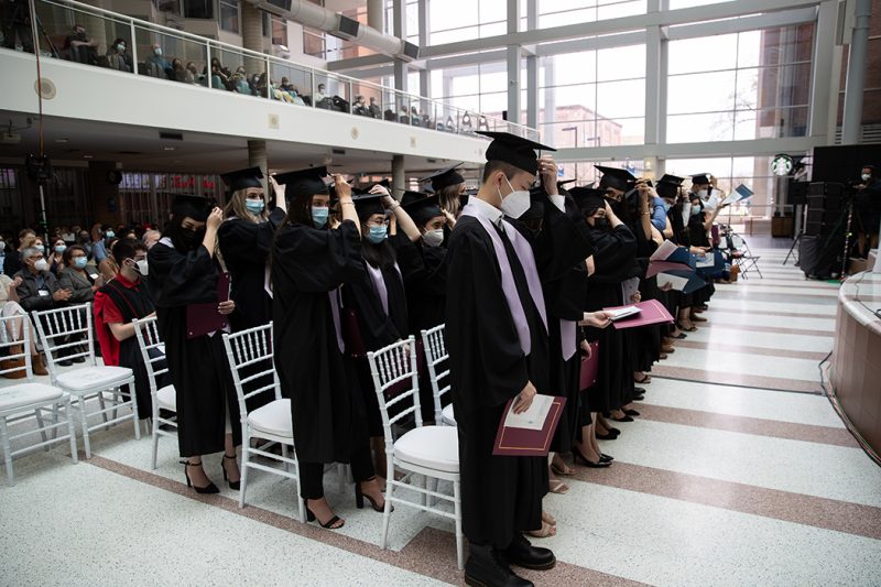 A group of graduates move the tassel to the left side of their caps.
