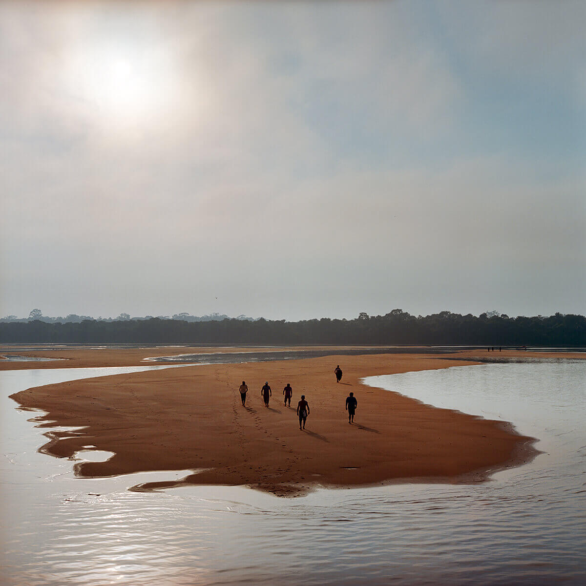 A photo of people walking out on a sandy beach toward water.