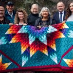 A group of people holding a star blanket.