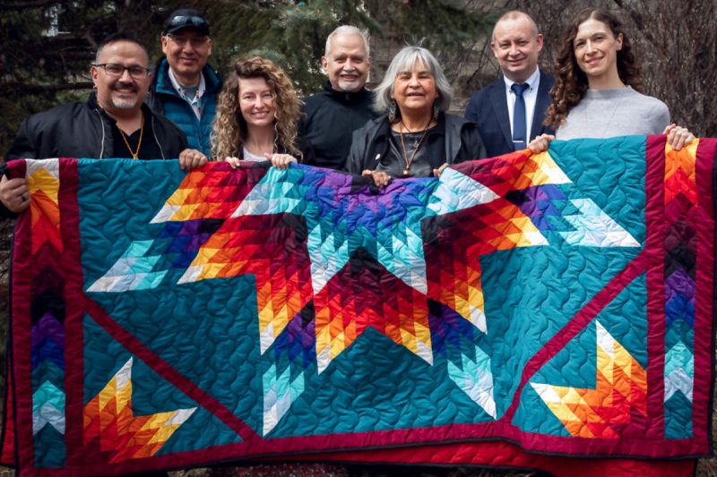 A group of people holding a star blanket.