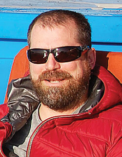 A headshot of CJ Mundy with sunglasses on a boat.