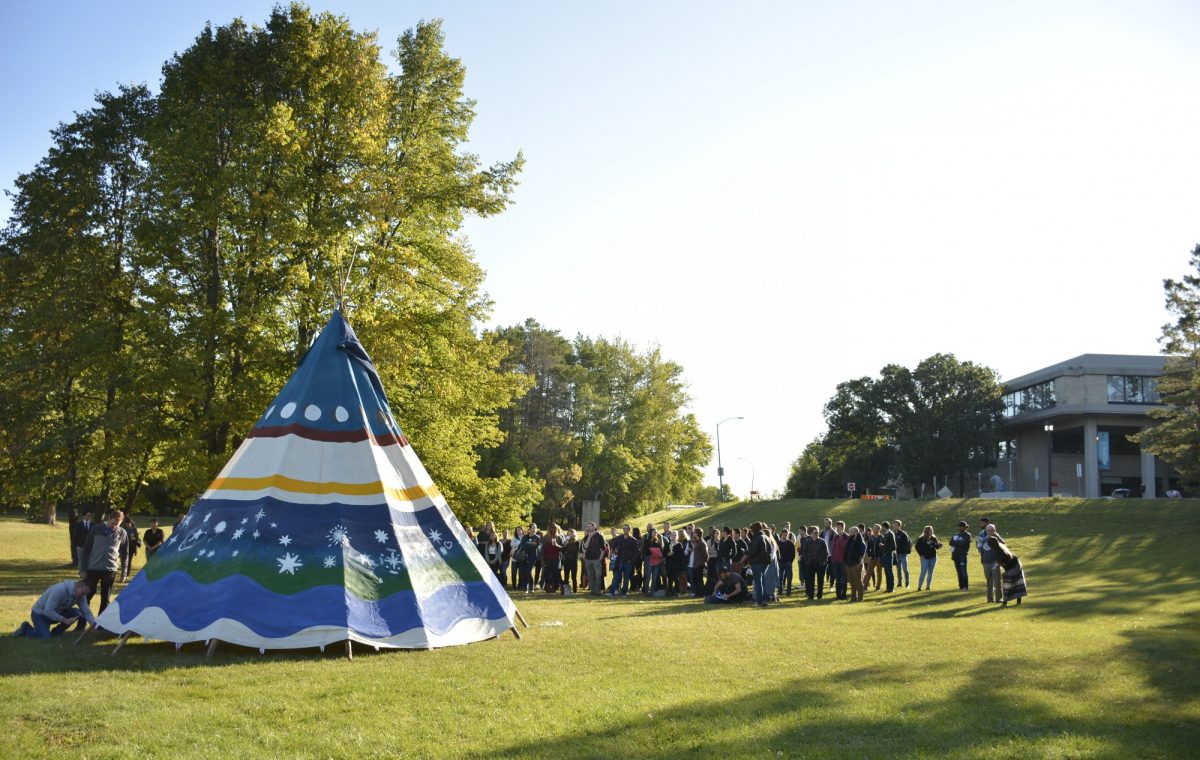 Law students surrounding a Tipi with Robson Hall in the background