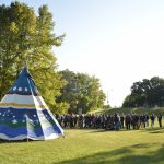 Law students surrounding a Tipi with Robson Hall in the background