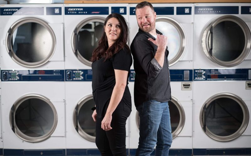 Photo of man and woman standing in front of laundry machines.