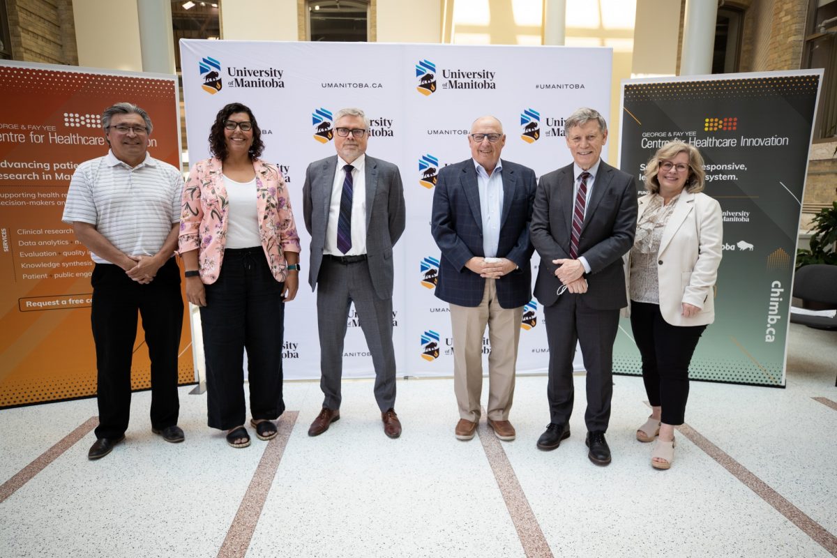 Six people who were involved in the June 27 announcement of SPOR funding stand on the stage in the Brodie Centre.