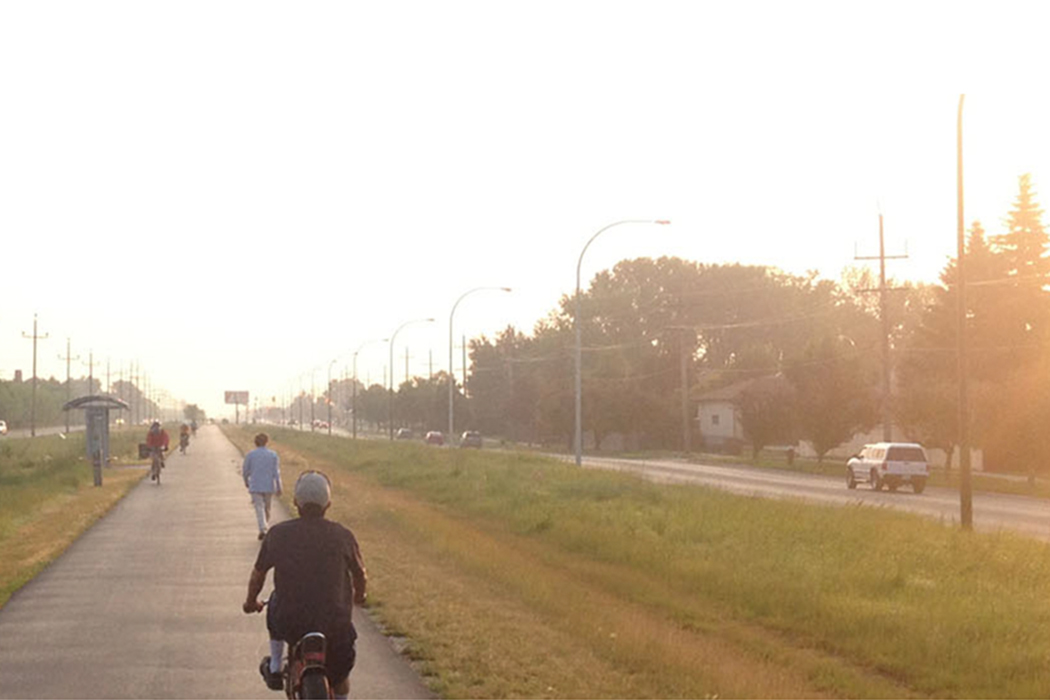 Four cyclists and a pedestrian use a multi-use trail.