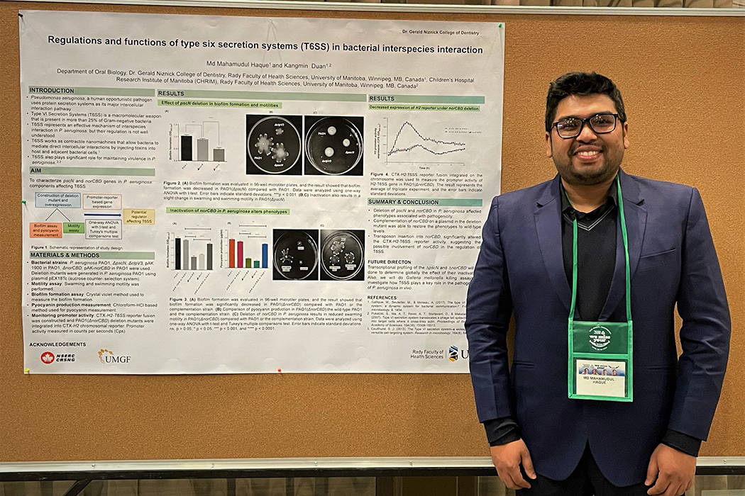 Mahamud Haque stands in front of his poster that is pinned to a bulletin board.