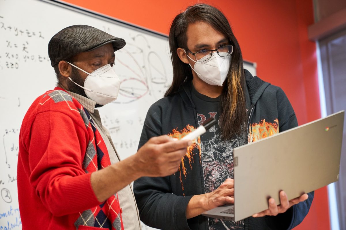 Student and instructor looking at laptop together