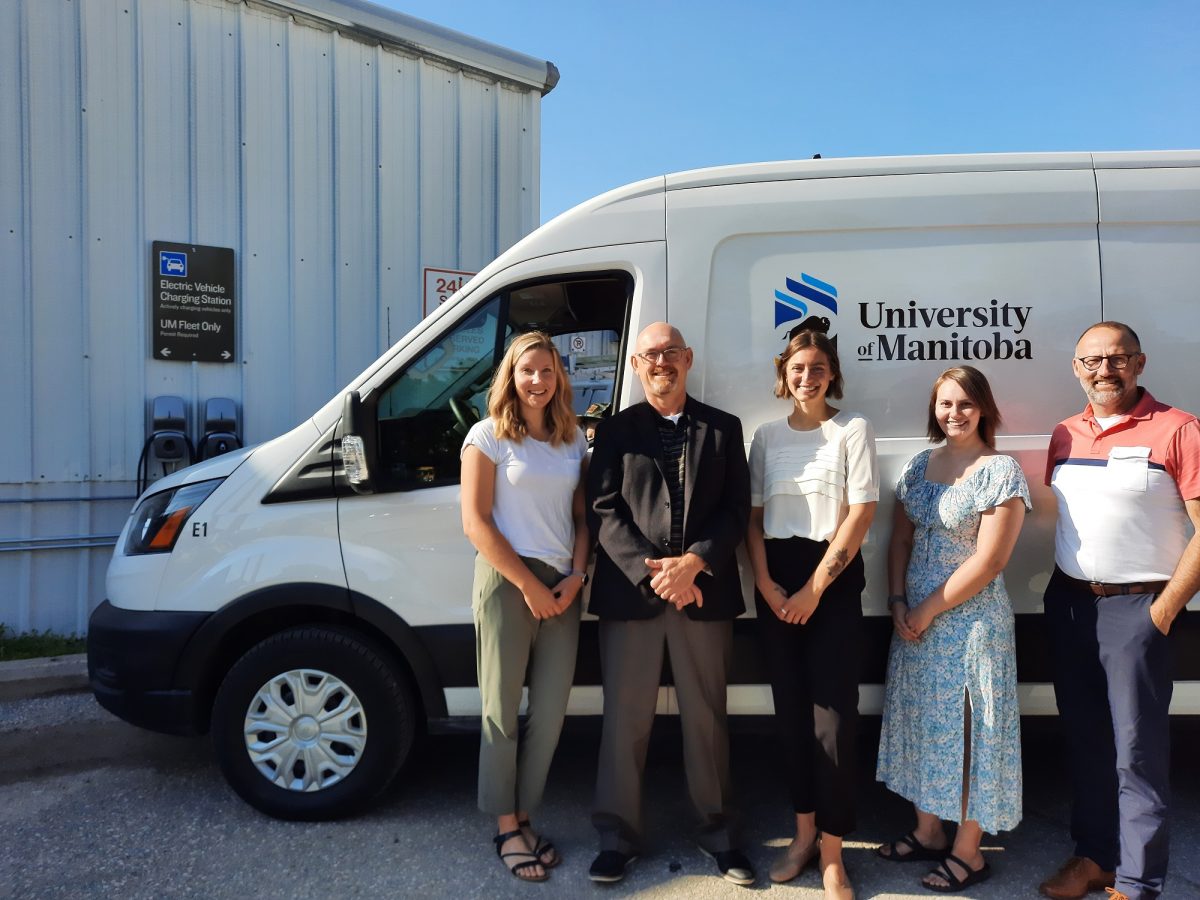 UM staff stand in front of a new electric fleet vehicle.