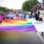 People hold a large UM Pride flag on Memorial Avenue in Winnipeg. Photo from the Winnipeg Pride Parade 2022.